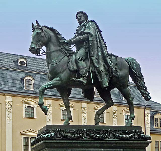 The bronze statue shows Carl August - duke and later grand-duke of Saxony-Weimar-Eisenach - on horseback in a general´s uniform with a garland made of laurel, oak leafs and flowers. The heroic interpretation inspired by the antique works of art refers to his participation in the wars of liberation in 1814. This work by local sculptor Adolf von Donndorf was unveiled in 1875 in order to celebrate the 100th anniversary of Carl August´s reign.